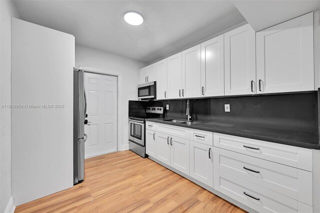 1355 NW 121st St, North Miami, FL 33167 - kitchen featuring stainless steel appliances, dark countertops, white cabinetry, and light wood-style flooring