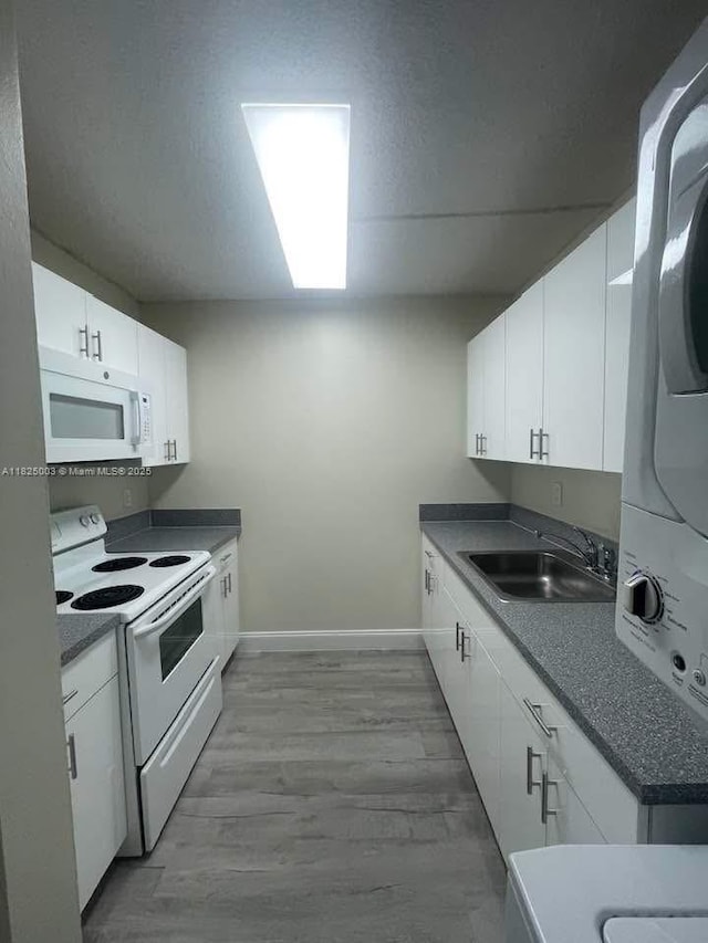 8260 SW 210th St Unit 320, Cutler Bay, FL 33189 - kitchen with white appliances, stacked washer / drying machine, white cabinets, and wood finished floors