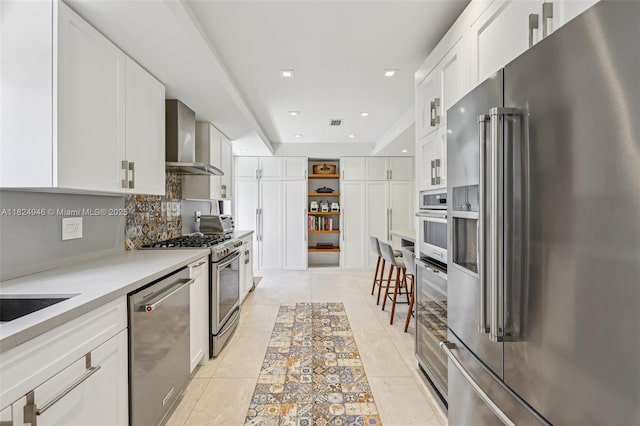 441 SW 27th Rd, Miami, FL 33129 - kitchen with stainless steel appliances, wall chimney exhaust hood, white cabinets, backsplash, and light tile patterned flooring