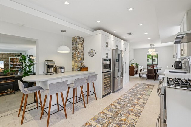 441 SW 27th Rd, Miami, FL 33129 - kitchen featuring appliances with stainless steel finishes, wine cooler, white cabinets, a kitchen bar, and decorative light fixtures