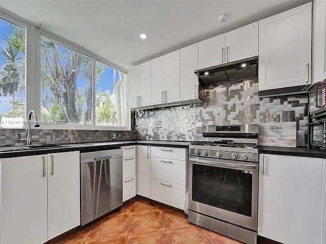 1607 Moffett St, Hollywood, FL 33020 - kitchen with appliances with stainless steel finishes, under cabinet range hood, dark countertops, backsplash, and recessed lighting