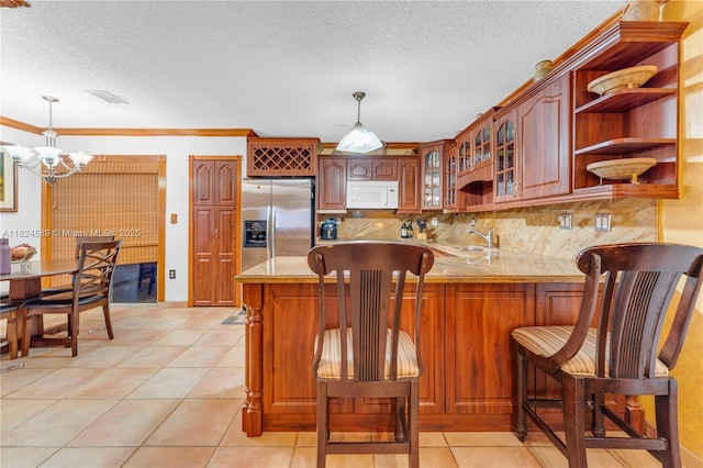 12350 NW 7th Trl, Miami, FL 33182 - kitchen with white microwave, a chandelier, a peninsula, light countertops, and stainless steel fridge