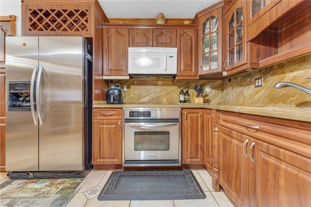 12350 NW 7th Trl, Miami, FL 33182 - kitchen with stainless steel appliances, light tile patterned floors, backsplash, and brown cabinets