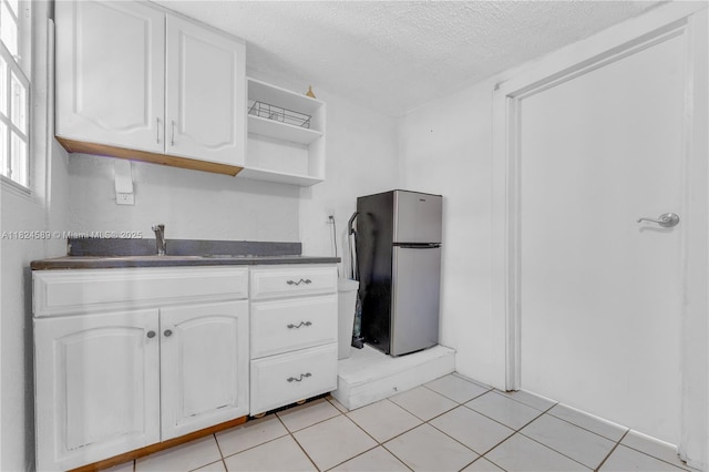 12350 NW 7th Trl, Miami, FL 33182 - kitchen with freestanding refrigerator, dark countertops, open shelves, white cabinets, and a textured ceiling