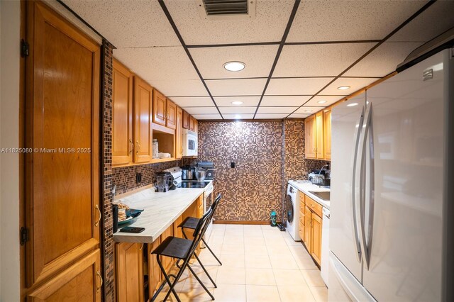 2101 Atlantic Shores Blvd Unit 120, Hallandale Beach, FL 33009 - kitchen with freestanding refrigerator, washer / dryer, a paneled ceiling, light countertops, and recessed lighting