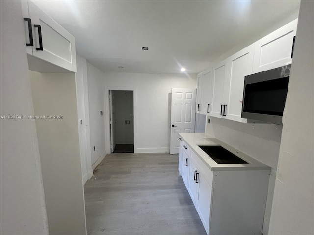 1800 SW 3rd St # B, Miami, FL 33135 - kitchen with stainless steel microwave, white cabinets, light wood-style flooring, black electric stovetop, and light countertops