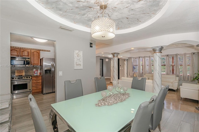11700 Sheridan St, Pembroke Pines, FL 33026 - dining room featuring ornate columns, a raised ceiling, arched walkways, and light wood-type flooring