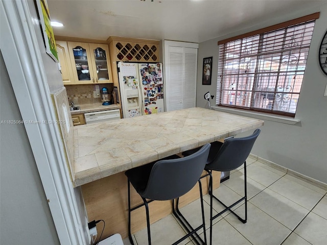 5328 W 26th Ave Unit 112, Hialeah, FL 33016 - kitchen featuring fridge with ice dispenser, a peninsula, glass insert cabinets, light tile patterned floors, and a kitchen breakfast bar
