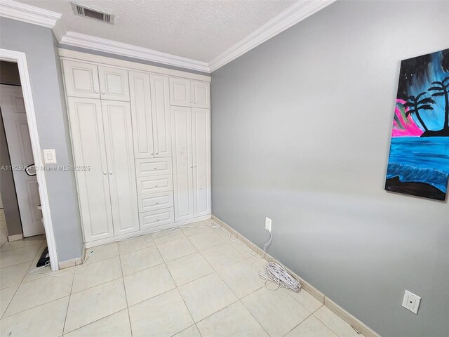 5328 W 26th Ave Unit 112, Hialeah, FL 33016 - unfurnished bedroom with crown molding, light tile patterned floors, a textured ceiling, and a closet