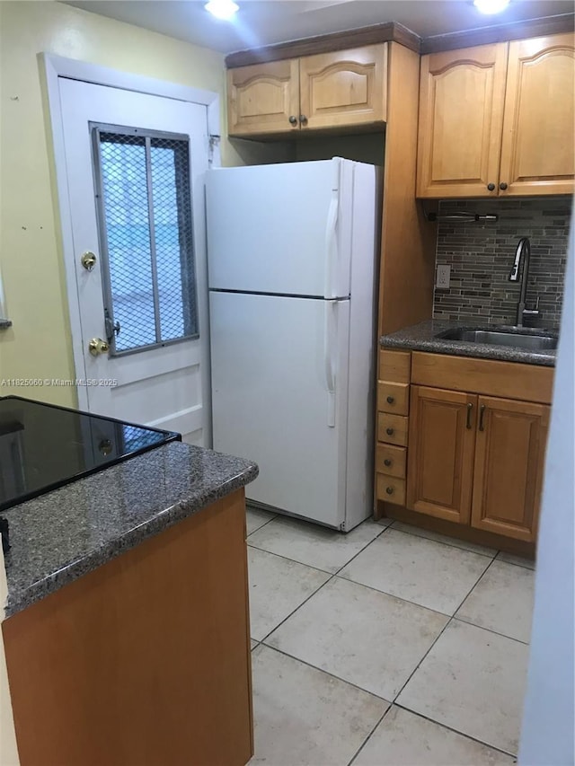 1145 Normandy Dr Unit 304, Miami Beach, FL 33141 - kitchen featuring freestanding refrigerator, tasteful backsplash, light tile patterned floors, dark stone counters, and brown cabinets