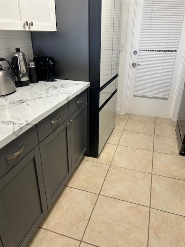 300 Golden Isles Dr Unit 311, Hallandale Beach, FL 33009 - kitchen with decorative backsplash, light tile patterned floors, and light stone countertops
