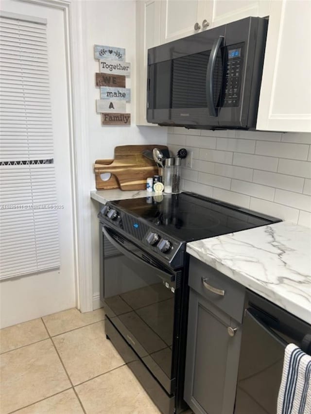 300 Golden Isles Dr Unit 311, Hallandale Beach, FL 33009 - kitchen with black appliances, light stone countertops, decorative backsplash, and light tile patterned floors