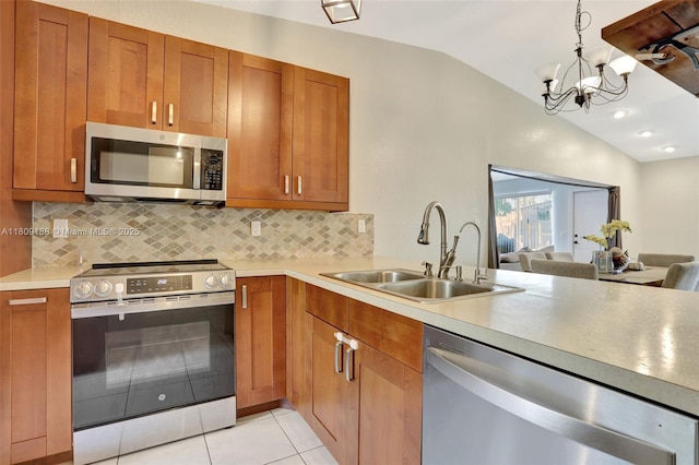 453 Lakewood Cir Unit A, Margate, FL 33063 - kitchen with stainless steel appliances, lofted ceiling, tasteful backsplash, brown cabinets, and a chandelier