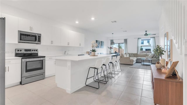 25564 SW 108th Ave, Homestead, FL 33032 - kitchen with stainless steel appliances, a kitchen island, light countertops, a breakfast bar area, and recessed lighting