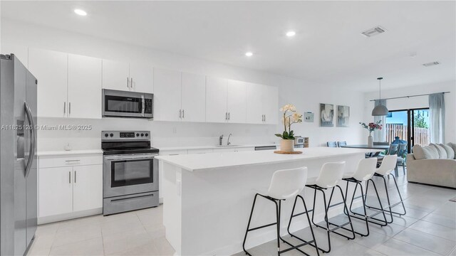 25564 SW 108th Ave, Homestead, FL 33032 - kitchen featuring appliances with stainless steel finishes, a breakfast bar, light tile patterned flooring, light countertops, and a center island