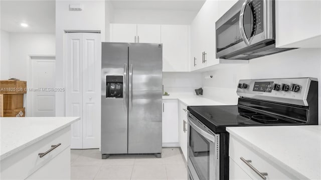 25564 SW 108th Ave, Homestead, FL 33032 - kitchen featuring appliances with stainless steel finishes, white cabinets, light tile patterned flooring, and light stone counters