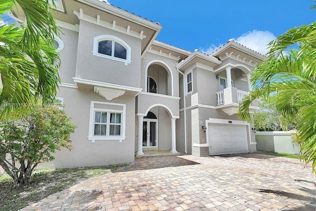 3521 Forest View Cir, Dania Beach, FL 33312 - mediterranean / spanish home with an attached garage, stucco siding, decorative driveway, a balcony, and french doors