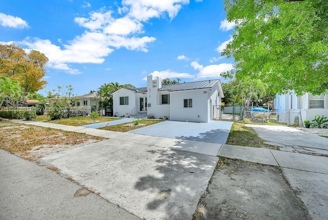 876 NE 81st St, Miami, FL 33138 - view of front of house featuring a gate, driveway, a standing seam roof, stucco siding, and a metal roof