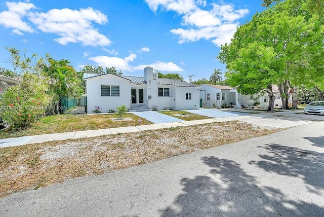 876 NE 81st St, Miami, FL 33138 - view of front facade with a chimney, a metal roof, a standing seam roof, stucco siding, and entry steps