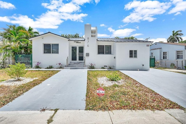 876 NE 81st St, Miami, FL 33138 - view of front of property with stucco siding, a standing seam roof, a chimney, a metal roof, and entry steps