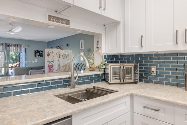 5725 Pelican Pointe, Sebastian, FL 32958 - kitchen featuring decorative backsplash, white cabinetry, ceiling fan, and open floor plan