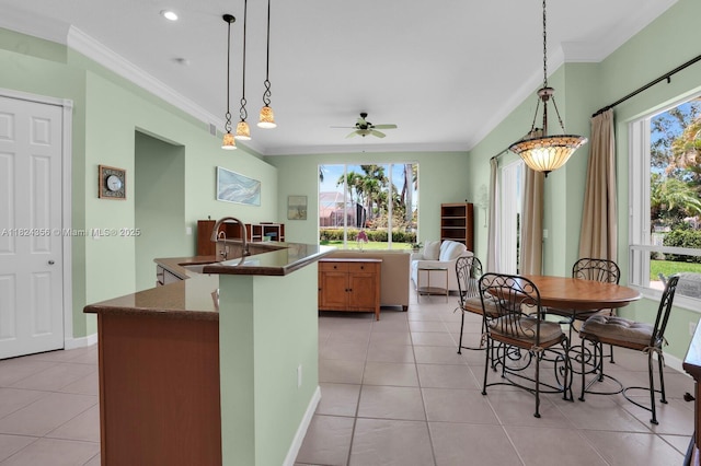 819 SW Bromelia Ter, Stuart, FL 34997 - kitchen with crown molding, a center island with sink, dark countertops, plenty of natural light, and light tile patterned flooring