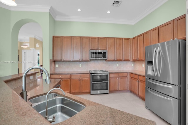819 SW Bromelia Ter, Stuart, FL 34997 - kitchen featuring appliances with stainless steel finishes, arched walkways, backsplash, crown molding, and light stone countertops