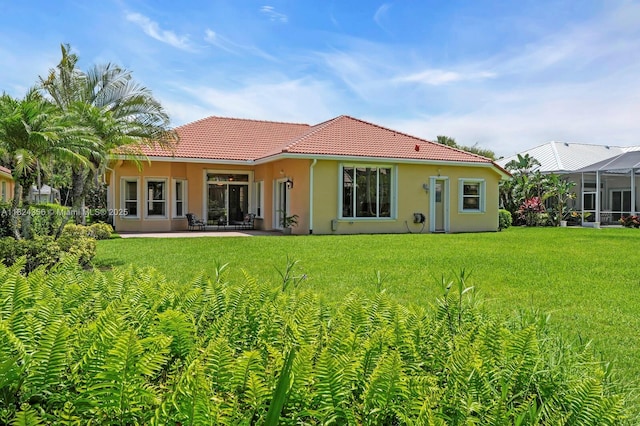 819 SW Bromelia Ter, Stuart, FL 34997 - back of property featuring a tiled roof, stucco siding, a lawn, and a patio