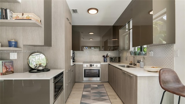 3020 SW 2nd Ave, Miami, FL 33129 - kitchen with stainless steel oven, modern cabinets, tasteful backsplash, light countertops, and light wood-style floors