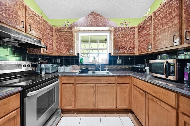 5610 NW 54th Ave, Tamarac, FL 33319 - kitchen featuring stainless steel appliances, under cabinet range hood, a textured ceiling, tasteful backsplash, and light tile patterned flooring