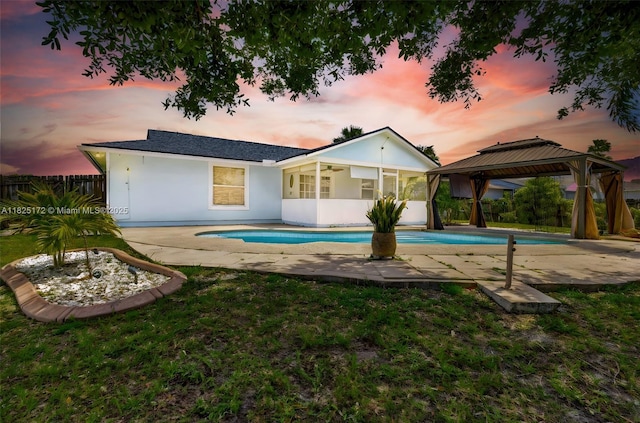 509 SW Hamburg Ter, Port St Lucie, FL 34984 - back of property at dusk with stucco siding, a gazebo, a patio, and a sunroom