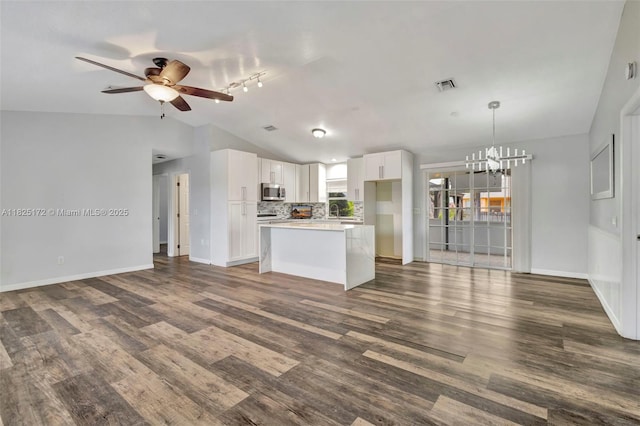 509 SW Hamburg Ter, Port St Lucie, FL 34984 - kitchen with stainless steel microwave, open floor plan, vaulted ceiling, a chandelier, and a ceiling fan