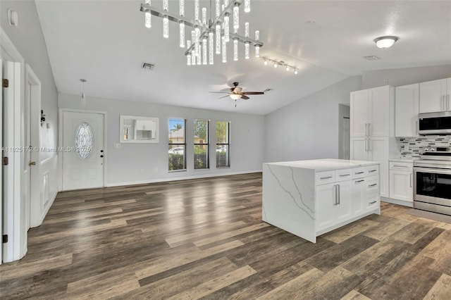 509 SW Hamburg Ter, Port St Lucie, FL 34984 - kitchen featuring appliances with stainless steel finishes, vaulted ceiling, wood finished floors, white cabinets, and a ceiling fan