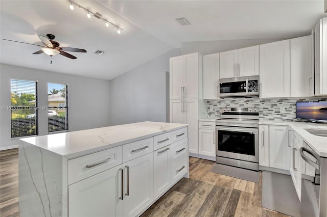 509 SW Hamburg Ter, Port St Lucie, FL 34984 - kitchen featuring appliances with stainless steel finishes, vaulted ceiling, light wood-style flooring, decorative backsplash, and ceiling fan