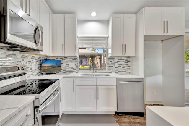 509 SW Hamburg Ter, Port St Lucie, FL 34984 - kitchen featuring appliances with stainless steel finishes, white cabinets, light stone counters, tasteful backsplash, and plenty of natural light
