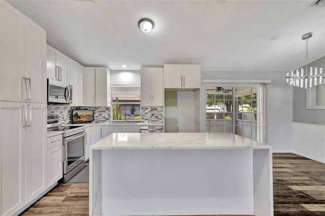 509 SW Hamburg Ter, Port St Lucie, FL 34984 - kitchen with appliances with stainless steel finishes, wood finished floors, tasteful backsplash, and white cabinetry