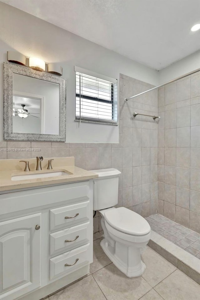 509 SW Hamburg Ter, Port St Lucie, FL 34984 - full bathroom featuring tile patterned floors, vanity, tiled shower, tile walls, and a ceiling fan