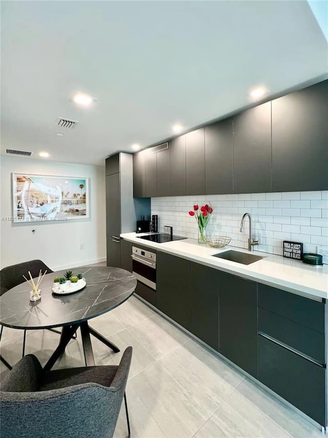 227 NE 2nd St Unit 2713, Miami, FL 33132 - kitchen featuring stainless steel oven, black electric cooktop, decorative backsplash, light countertops, and recessed lighting