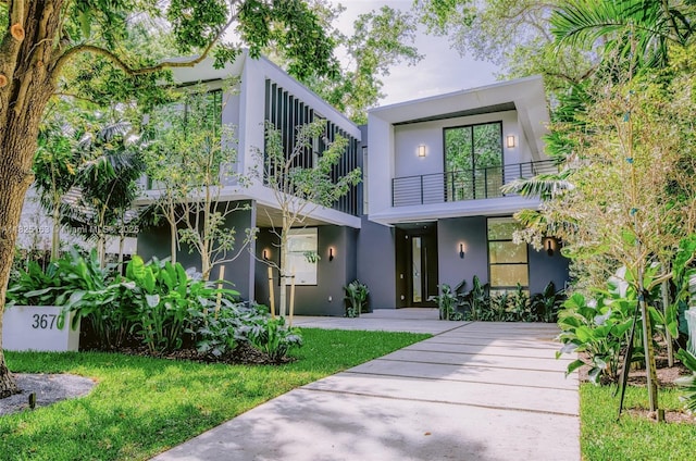 3670 Avocado Ave, Miami, FL 33133 - view of front of house with stucco siding, a balcony, and a front yard