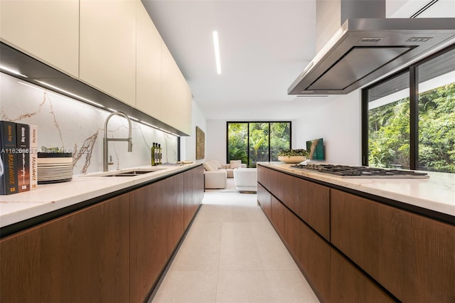 3670 Avocado Ave, Miami, FL 33133 - kitchen featuring extractor fan, light stone counters, stainless steel gas stovetop, open floor plan, and backsplash