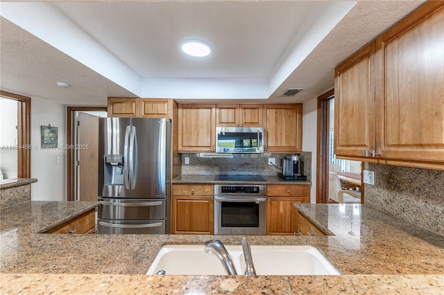 1460 NW 99th Ave, Plantation, FL 33322 - kitchen featuring appliances with stainless steel finishes, decorative backsplash, brown cabinets, and a raised ceiling