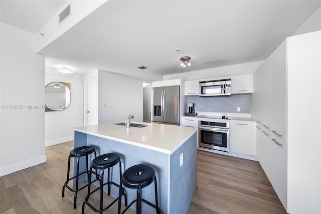 1900 N Bayshore Dr Unit 4111, Miami, FL 33132 - kitchen with stainless steel appliances, light wood-style flooring, white cabinetry, a breakfast bar area, and a kitchen island with sink