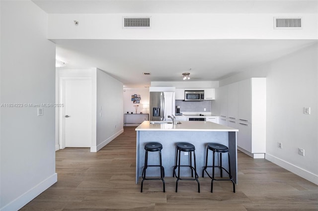 1900 N Bayshore Dr Unit 4111, Miami, FL 33132 - kitchen featuring appliances with stainless steel finishes, white cabinets, a breakfast bar, light countertops, and a kitchen island with sink