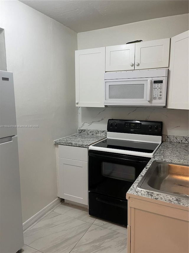 6214 SW 131st Ct Unit 103, Miami, FL 33183 - kitchen with white microwave, freestanding refrigerator, range with electric cooktop, light marble finish floors, and white cabinets