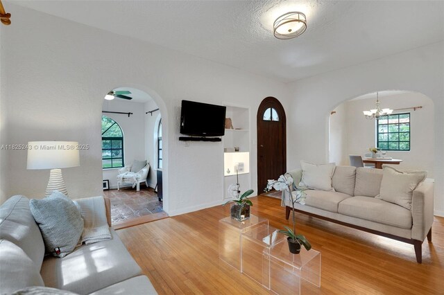 425 Cadagua Ave, Coral Gables, FL 33146 - living room with arched walkways, wood finished floors, healthy amount of natural light, and a chandelier