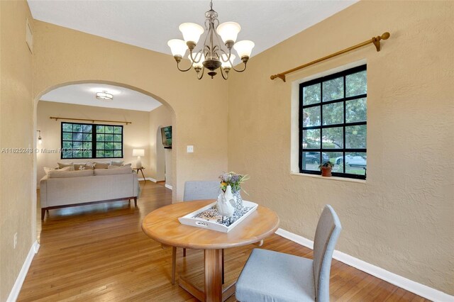 425 Cadagua Ave, Coral Gables, FL 33146 - dining area with arched walkways, wood finished floors, a chandelier, and a textured wall