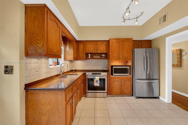 425 Cadagua Ave, Coral Gables, FL 33146 - kitchen with stainless steel appliances, brown cabinets, tasteful backsplash, and light tile patterned flooring
