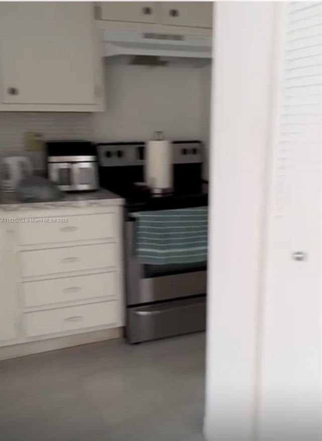 251 174th St Unit 1210, Sunny Isles Beach, FL 33160 - kitchen featuring stainless steel range with electric cooktop, under cabinet range hood, white cabinetry, light countertops, and concrete flooring