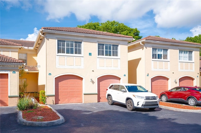 2406 Centergate Dr Unit 202, Miramar, FL 33025 - view of front of property with a garage, stucco siding, a tiled roof, and driveway