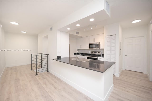 2406 Centergate Dr Unit 202, Miramar, FL 33025 - kitchen with appliances with stainless steel finishes, light wood-type flooring, a peninsula, white cabinetry, and recessed lighting